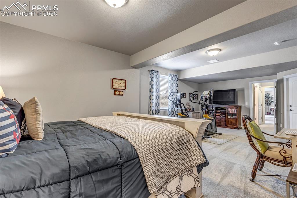 Image 42 of 50: Carpeted bedroom featuring a textured ceiling and baseboards