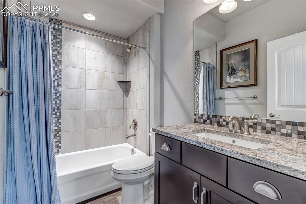 Image 43 of 50: Full bathroom featuring a textured wall, vanity, a stall shower, dark wood-