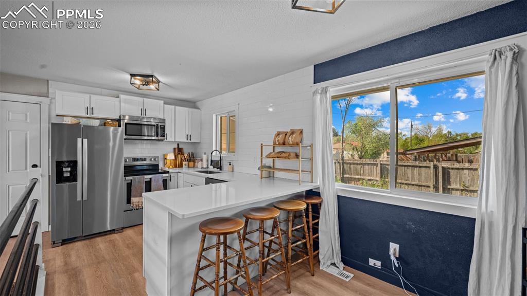 Image 10 of 42: Contemporary kitchen featuring white cabinetry, stainless steel appliances,