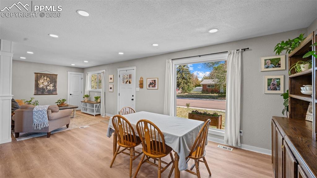 Image 12 of 42: Open-concept dining and living area featuring wood-finish flooring, recesse