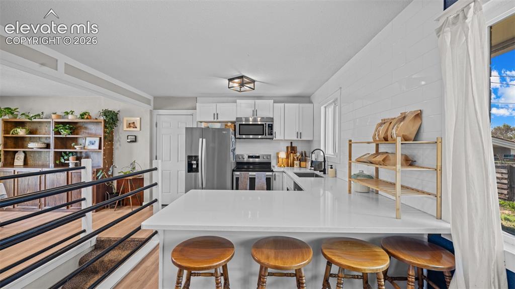 Image 12 of 43: Modern kitchen featuring white cabinetry, stainless steel appliances, and a