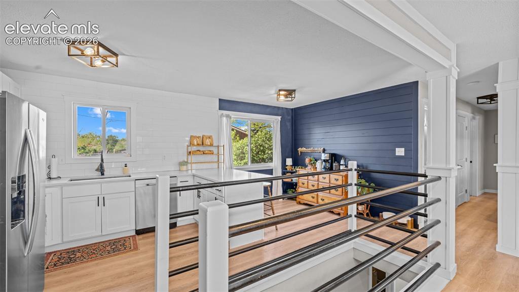 Image 14 of 43: Open-concept living space featuring a kitchen with white cabinetry, stainle