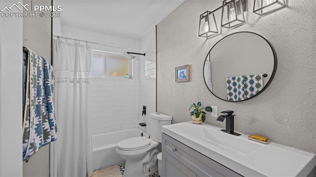 Image 15 of 42: Bathroom featuring a single vanity with an integrated white sink, a black-f