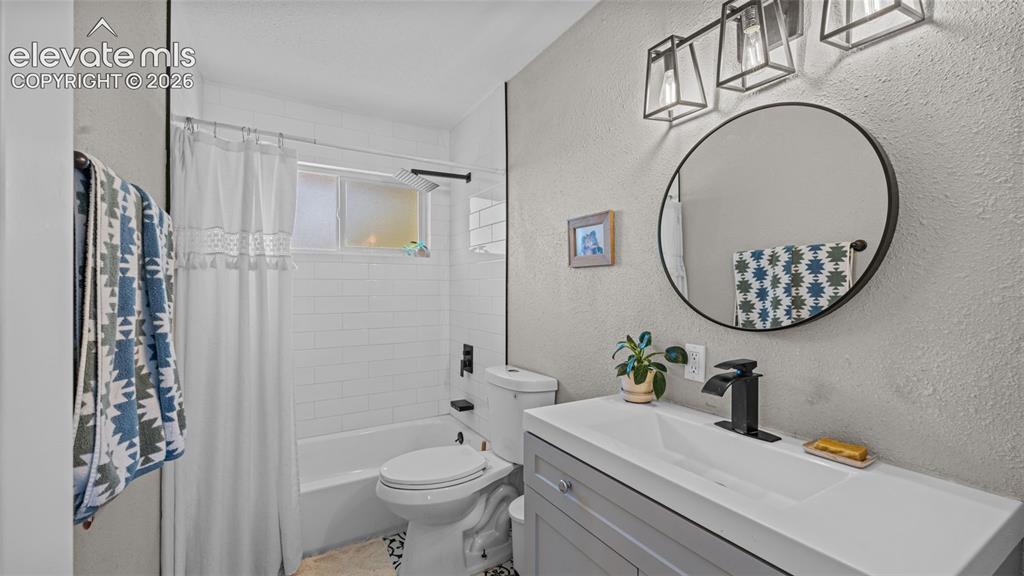 Image 16 of 43: Bathroom featuring a single vanity with an integrated white sink, a black-f