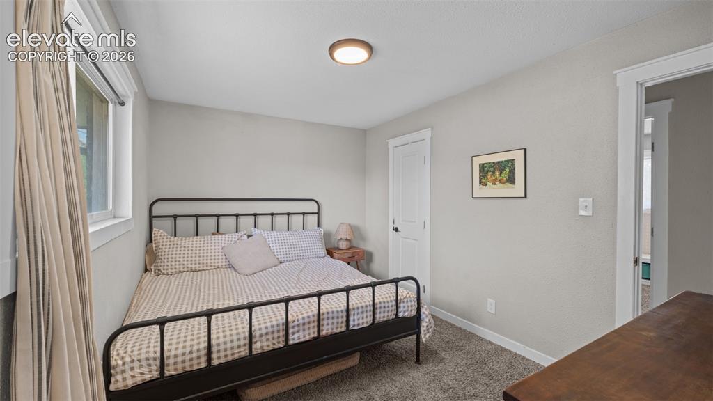 Image 20 of 43: Carpeted bedroom featuring a window with natural light, a white paneled doo