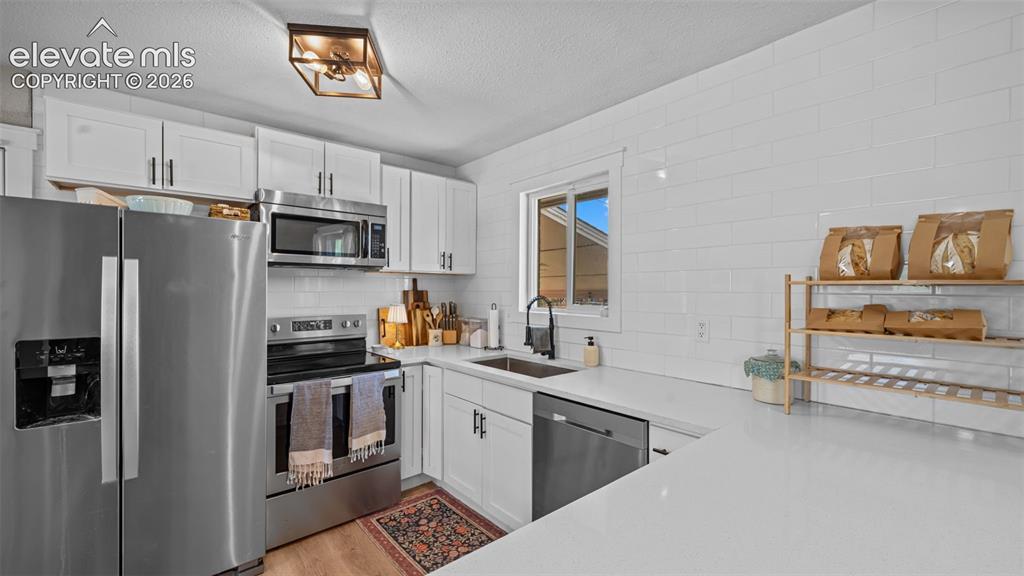 Image 22 of 43: Kitchen featuring white cabinetry, stainless steel appliances, white subway