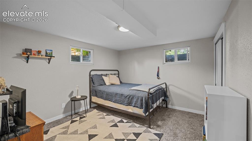 Image 24 of 43: Carpeted room with light gray walls, two windows, and a built-in closet wit
