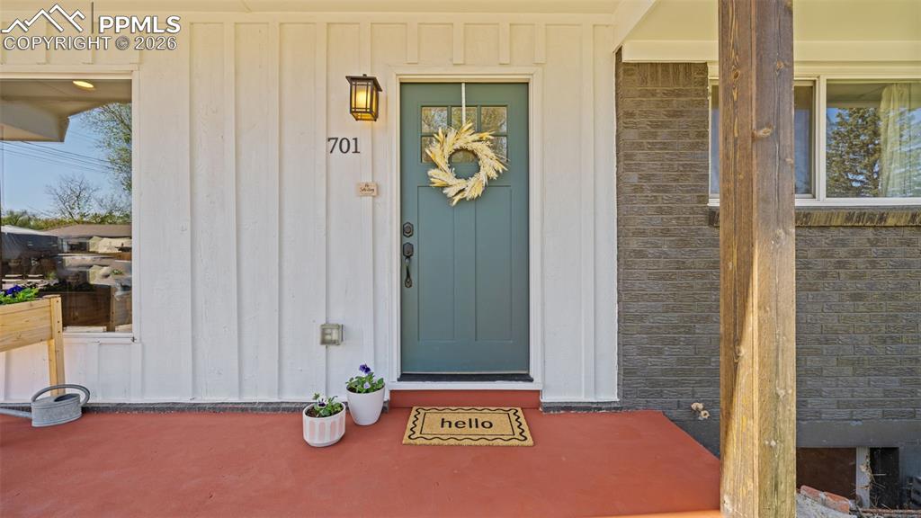 Image 3 of 42: Inviting front entrance featuring a teal door, white board and batten sidin