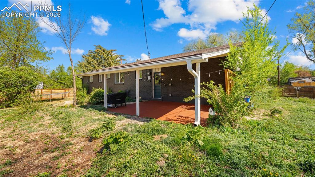 Image 30 of 42: Expansive backyard featuring a covered patio, dark brick exterior, and part
