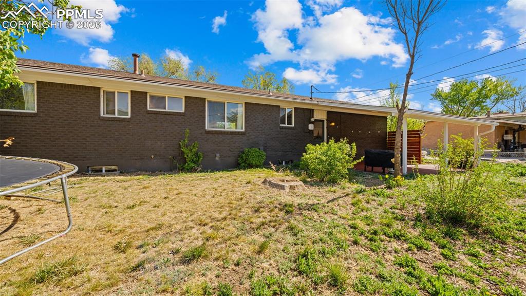 Image 31 of 42: Rear exterior of the property featuring a dark brick facade and multiple wi