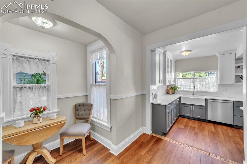 Image 14 of 49: Kitchen featuring gray cabinetry, dishwasher, arched walkways, light wood-t