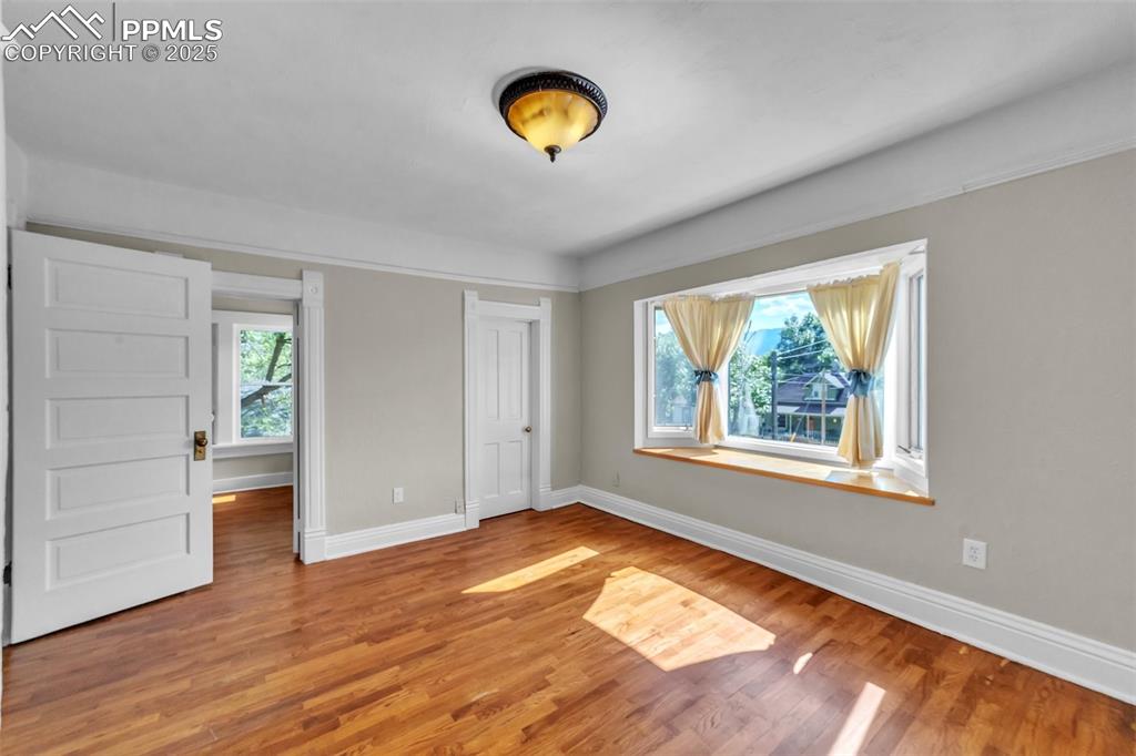 Image 21 of 49: Unfurnished bedroom featuring multiple windows and wood finished floors