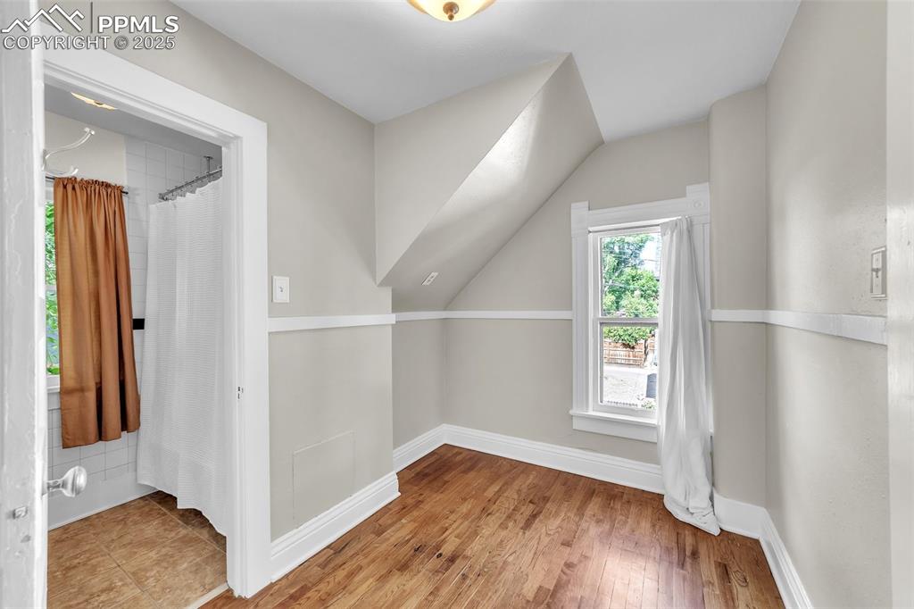 Image 27 of 49: Additional space with wood floors and lofted ceiling, in between bedroom an