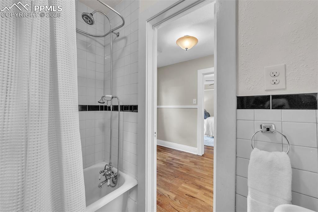 Image 29 of 49: Bathroom featuring shower / bath & original steel tub combination with curt