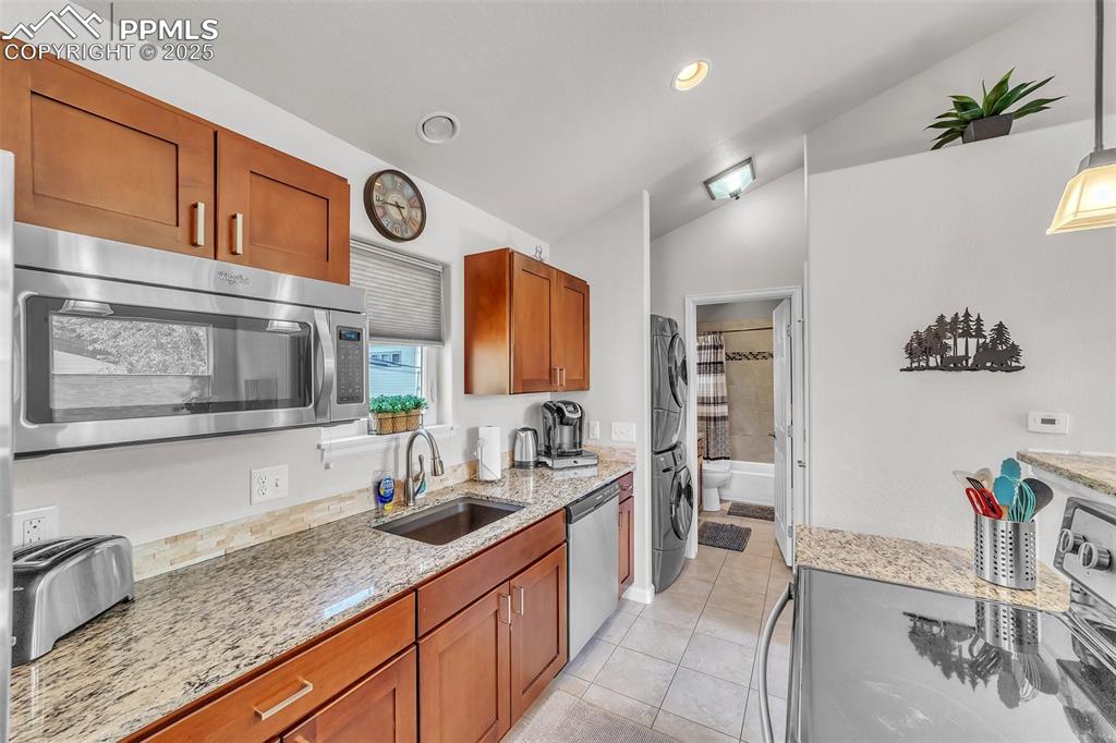 Image 31 of 49: Apartment: Kitchen with stainless steel appliances, stacked washer / dryer,