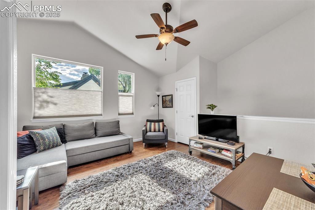 Image 36 of 49: Apartment: Living room featuring lofted ceiling, ceiling fan, and wood fini