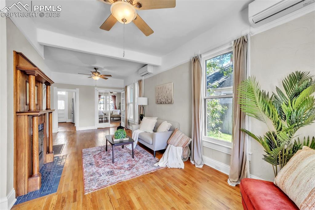 Image 4 of 49: Living area featuring an AC wall unit, a ceiling fan, wood finished floors,