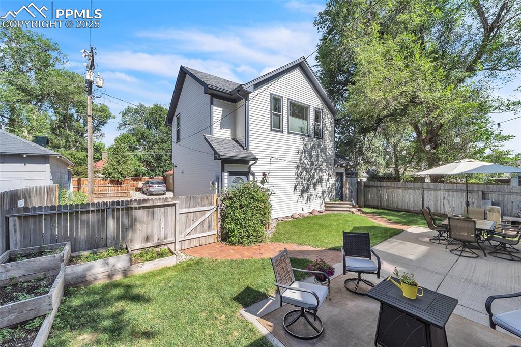 Image 40 of 49: Back of property with a vegetable garden, a fenced backyard, outdoor dining