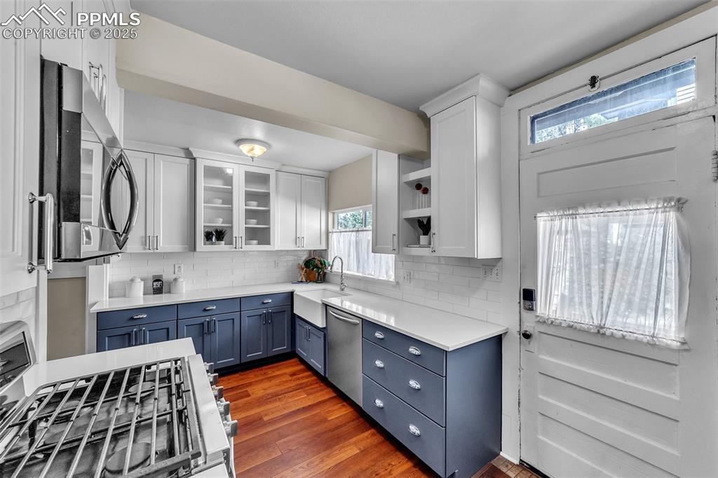 Image 9 of 49: Kitchen with stainless steel appliances, blue cabinets, white cabinetry, an