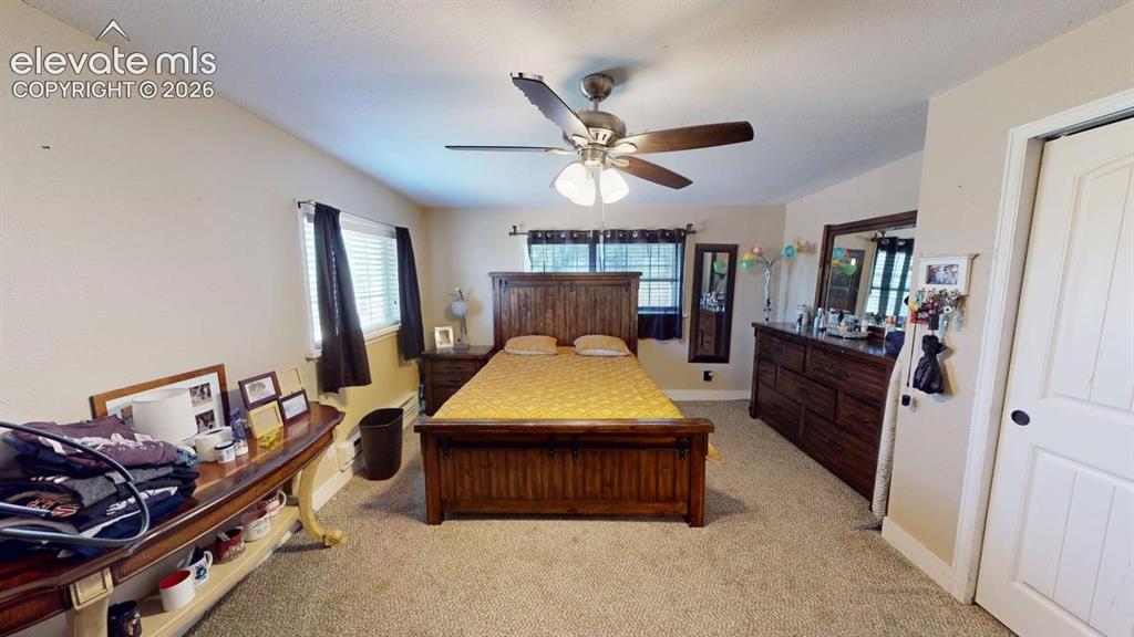 Image 12 of 23: Carpeted flooring, ceiling fan, white paneled door, and multiple windows wi