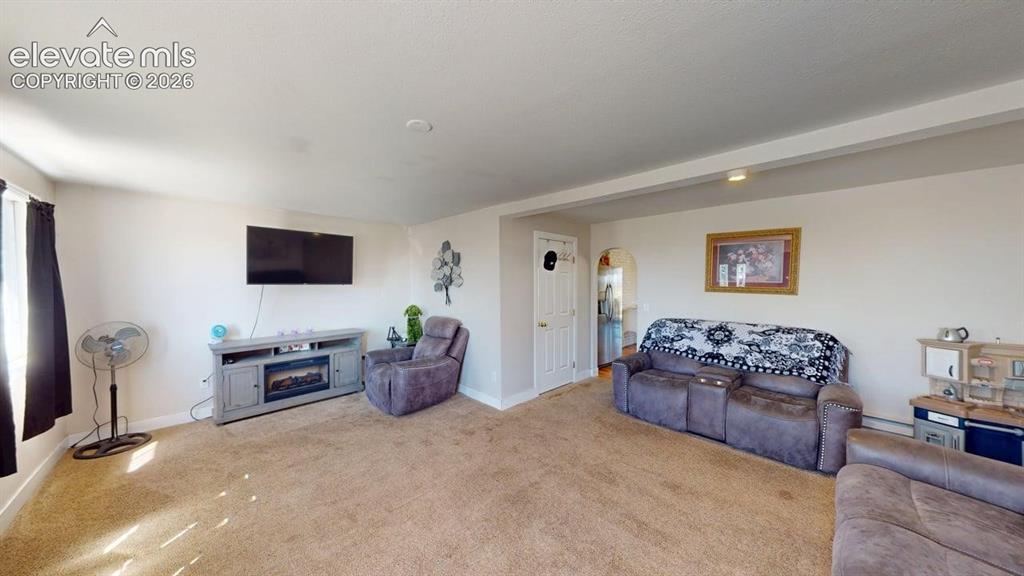 Image 8 of 23: Carpeted living area with light-colored walls and a window featuring dark-c