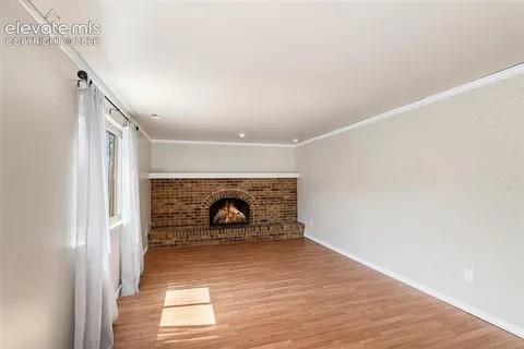 Image 19 of 26: Spacious interior family room featuring a brick fireplace, wood-finish floo