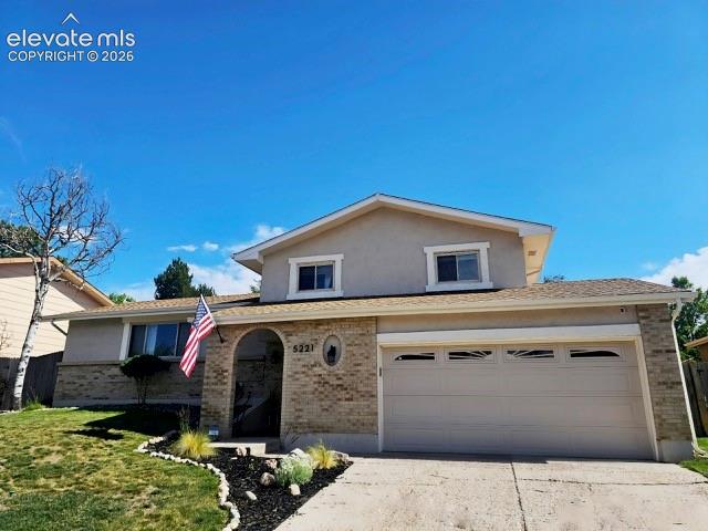 Image 2 of 26: Split-level residence featuring a two-car garage with decorative window ins