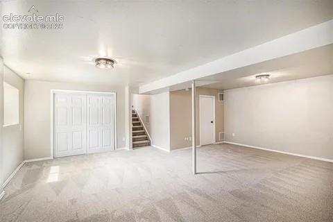 Image 23 of 26: Spacious lower-level room featuring light gray carpeting and neutral wall p