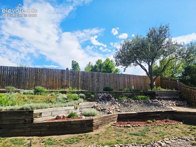 Image 25 of 26: Multi-tiered backyard landscaping featuring wood retaining walls, mature tr