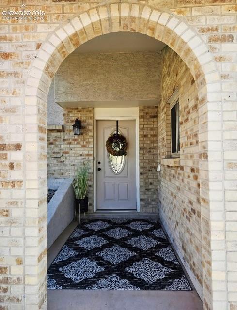 Image 4 of 26: Arched brick entryway featuring a light-colored brick facade
