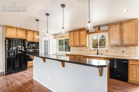 Image 7 of 26: Kitchen featuring wood-finish flooring, black appliances, a central island