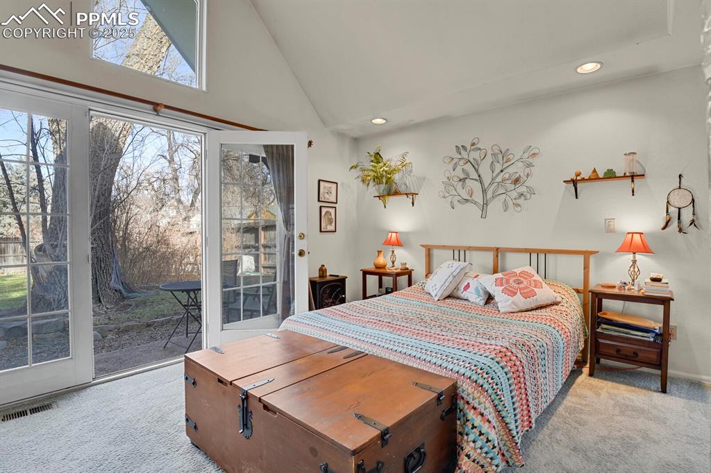 Image 14 of 34: Primary bedroom additon with vaulted ceiling and French doors leading out t