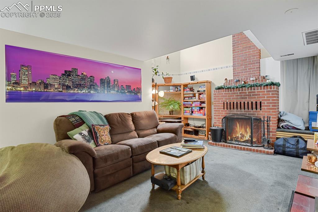 Image 27 of 34: Lower level family room with brick fireplace