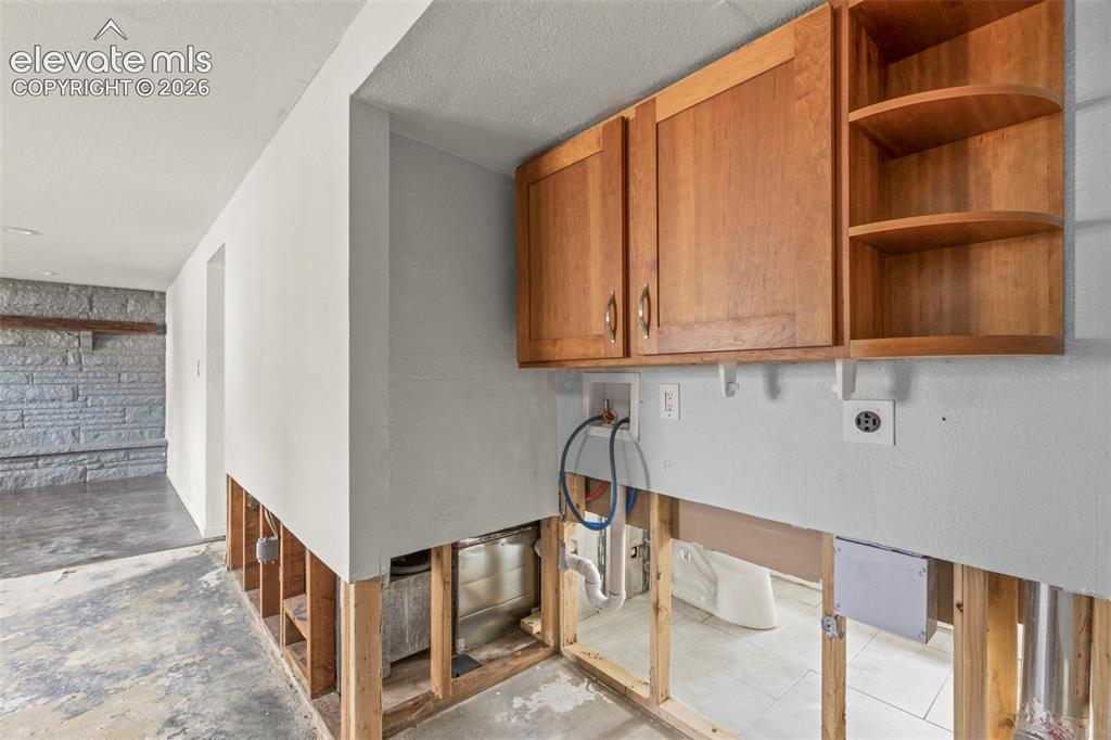 Image 16 of 24: Utility area with wood cabinetry, open shelving, and visible electrical and