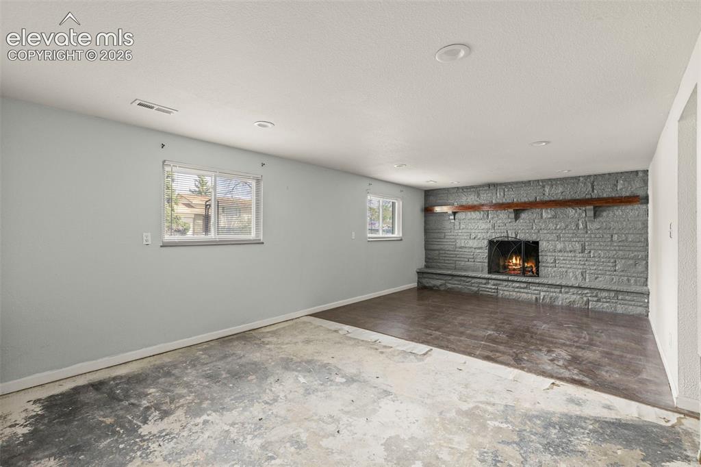 Image 17 of 24: Stone fireplace with a substantial wood mantelpiece
