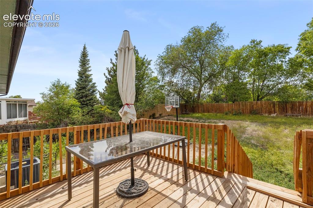 Image 24 of 24: Expansive wood deck with natural wood railings, overlooking a grassy backya