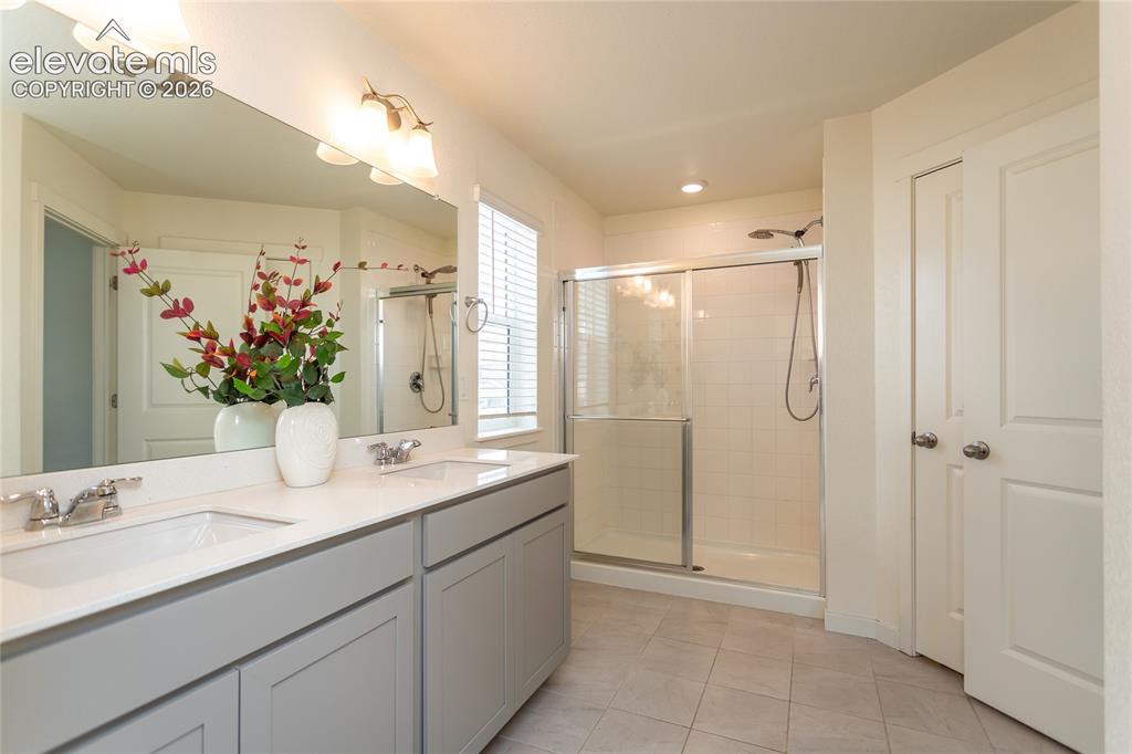Image 23 of 48: Beautiful primary bathroom has tile flooring and quartz contertops.
