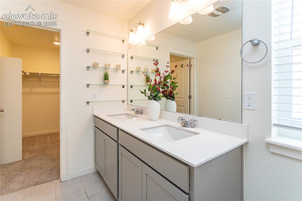 Image 24 of 48: Extended vanity with dual sinks and built-in glass shelving.