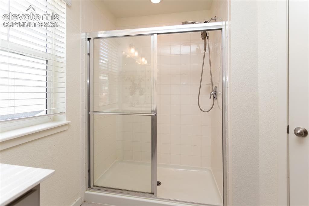 Image 25 of 48: Oversized shower with tile surround and glass doors.