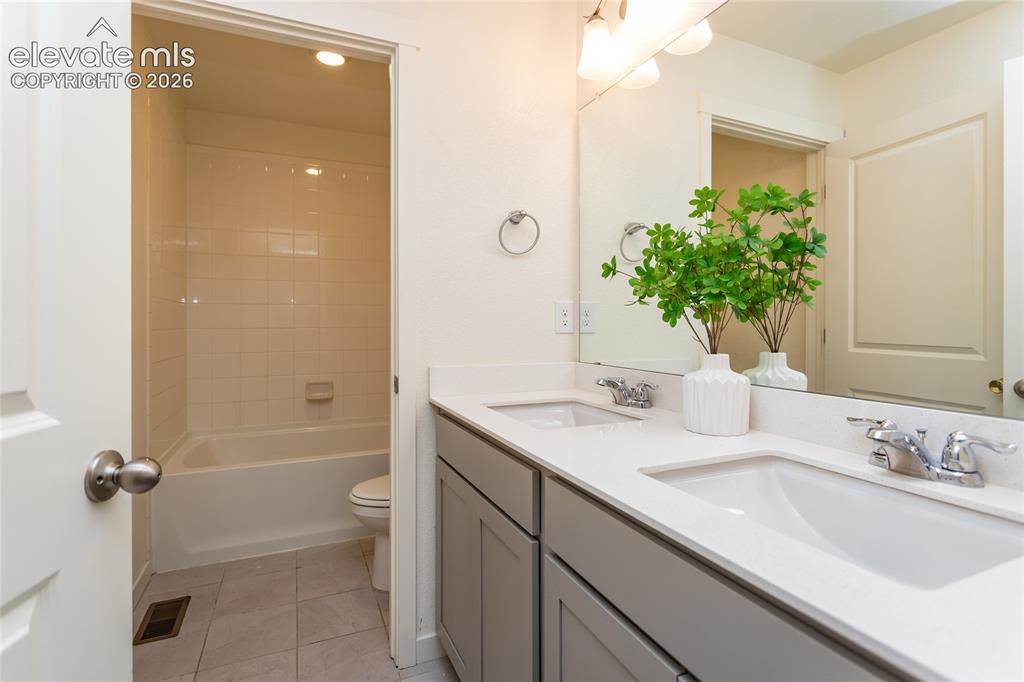 Image 27 of 48: Upper hall bathroom also offers dual sinks, quartz countertops and tile flo