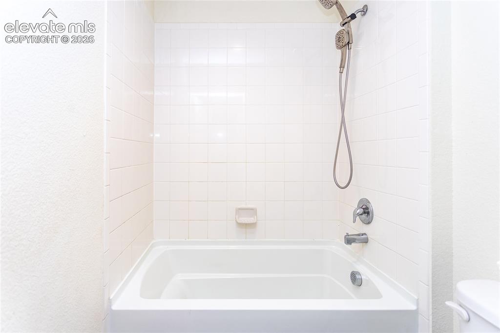 Image 28 of 48: Upper hall bathroom has a large tub with tile surround that is conveniently