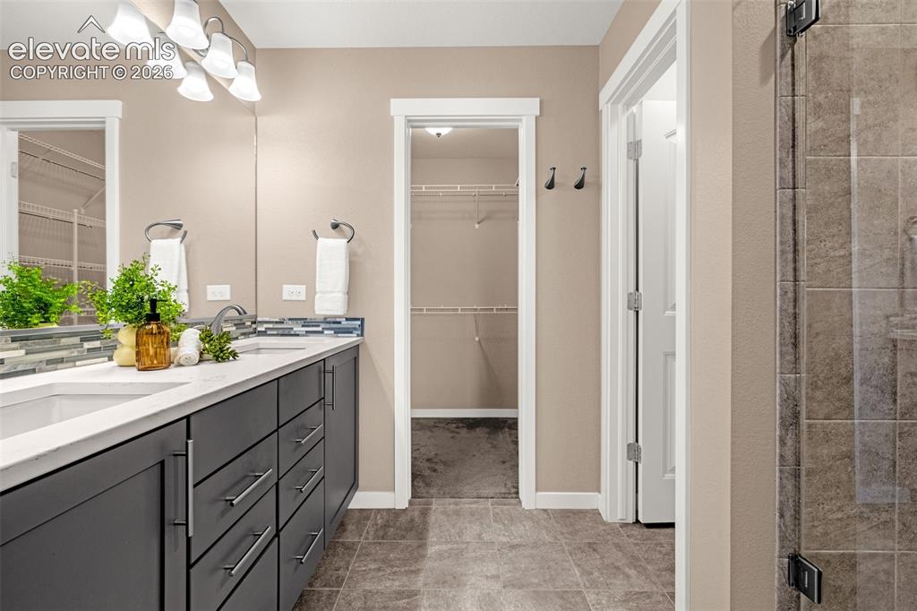 Image 17 of 28: Double vanity with dual undermount sinks, tile backsplash, and quartz count