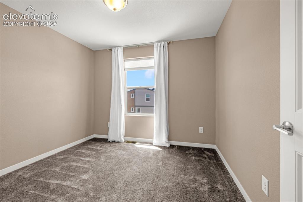 Image 22 of 32: Neutral-toned room featuring a single window with white trim, gray carpet f