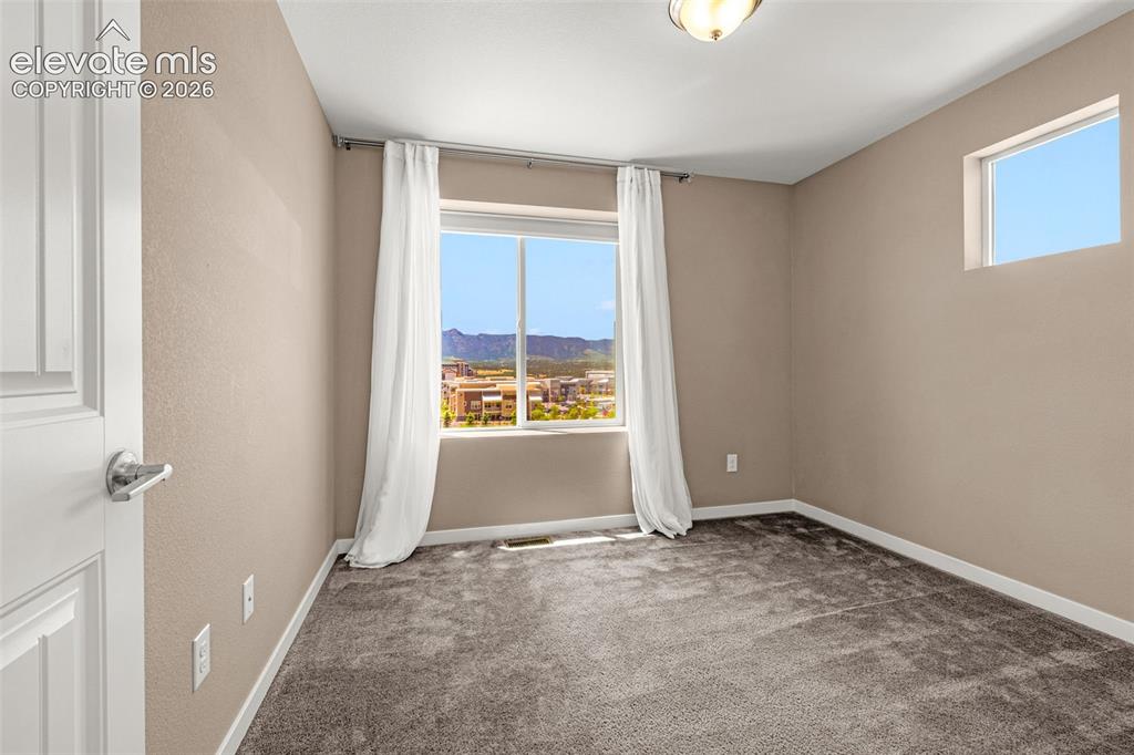 Image 22 of 28: Carpeted bedroom featuring a large window, a smaller upper window, and a ce
