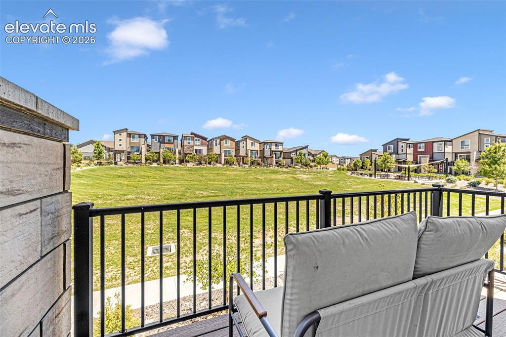 Image 25 of 32: Private balcony featuring a wood-finish deck, black metal railing, and cont
