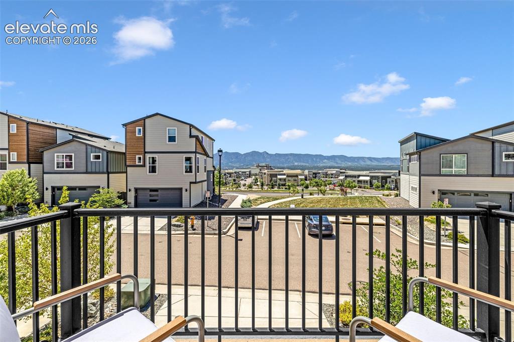 Image 25 of 28: Black metal balcony railing overlooking a street, modern residential archit