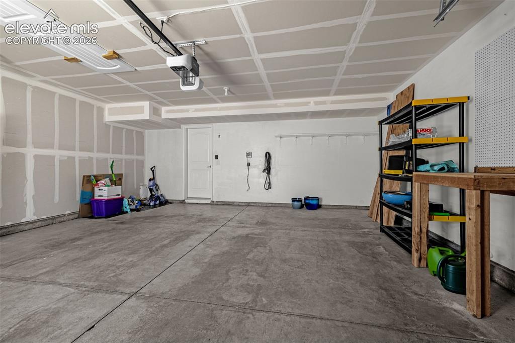 Image 26 of 28: Spacious garage with concrete flooring, automatic garage door opener, and a
