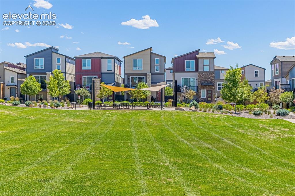 Image 27 of 28: Expansive green space featuring a shaded gathering area with outdoor seatin