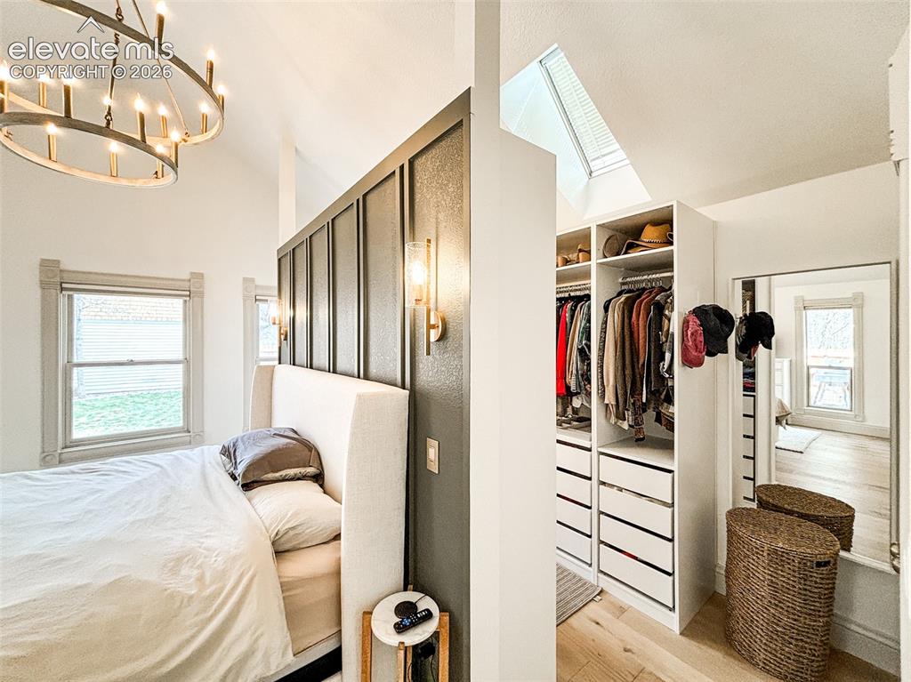 Image 12 of 33: Vaulted ceilings featuring a large chandelier and accent wall with sconce l