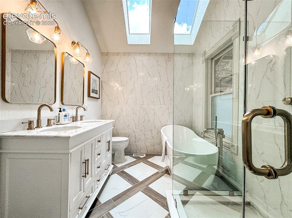 Image 13 of 33: Bathroom featuring a dual vanity with a white countertop and bronze-finish